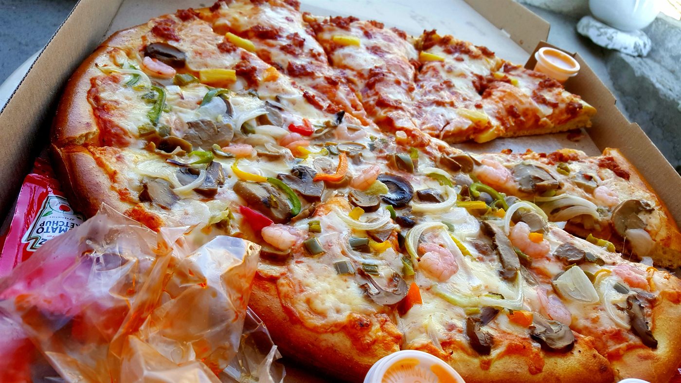 Pizza con pimiento, aceituna y jamón lista para entregar