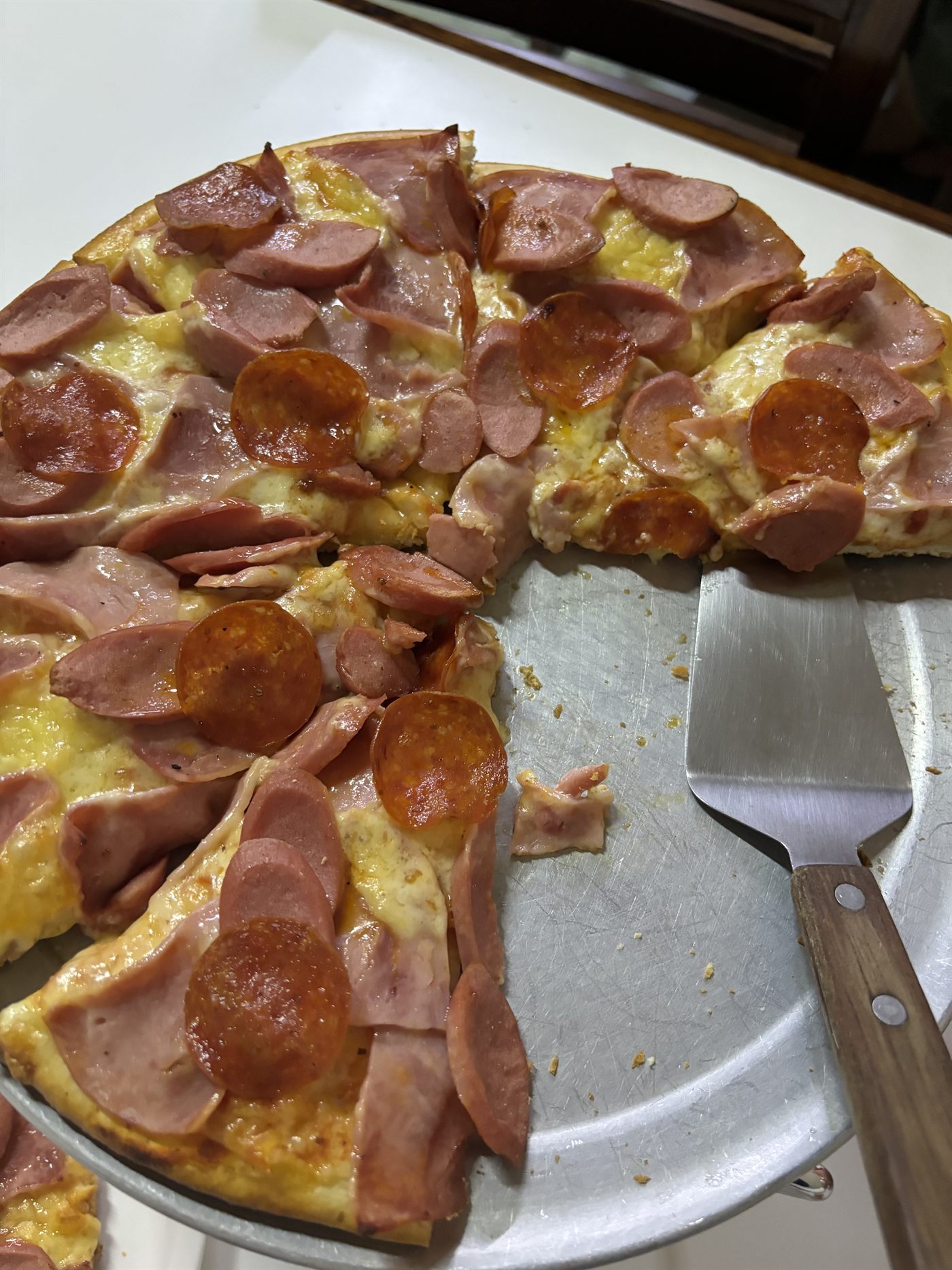 Pizza de pepperoni y salchicha con una rebanada levantada